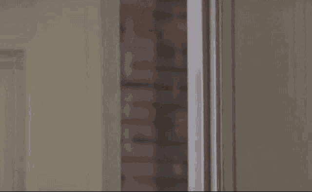 a man in a suit and tie is peeking out from behind a door and smiling .