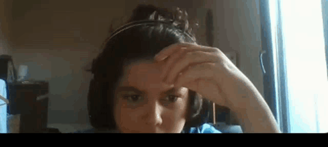 a woman wearing headphones is touching her forehead with her hand .