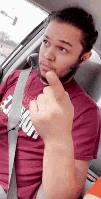 a man in a maroon shirt that says ' emerson ' on it is giving the middle finger