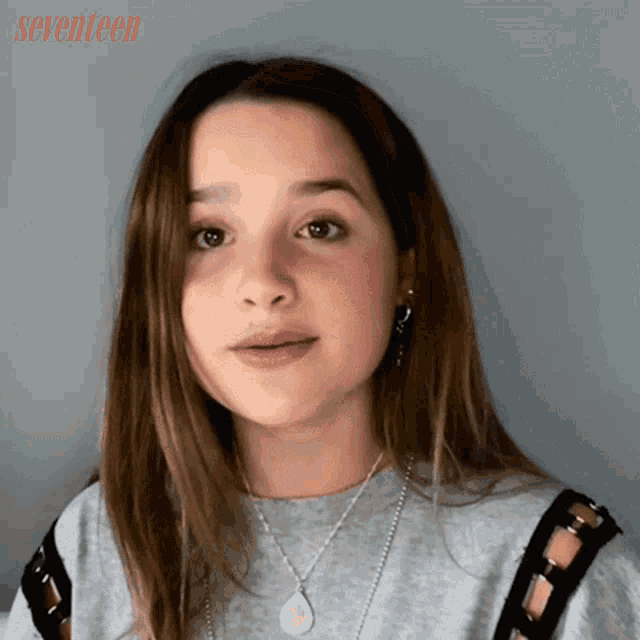 a girl wearing a necklace with a pendant that says seventeen