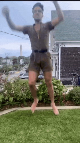 a man in a jumpsuit is jumping in the air with his arms outstretched .
