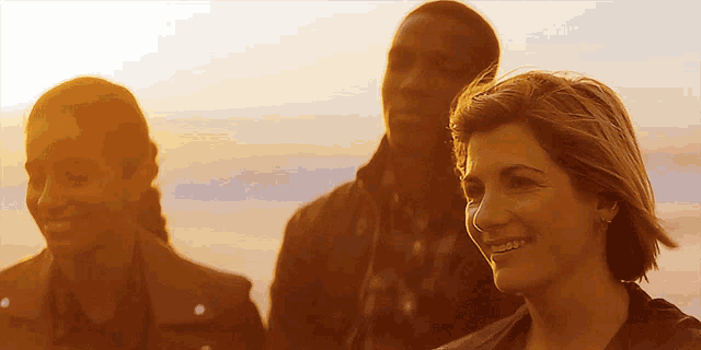 a man and two women are smiling for the camera at sunset