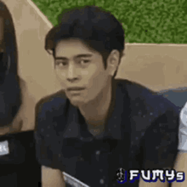 a man in a polka dot shirt is sitting next to a woman and looking at the camera .