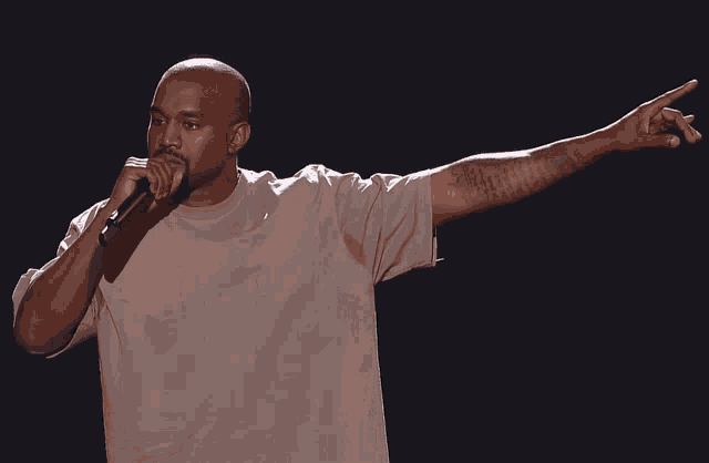 kanye west is holding a microphone and pointing