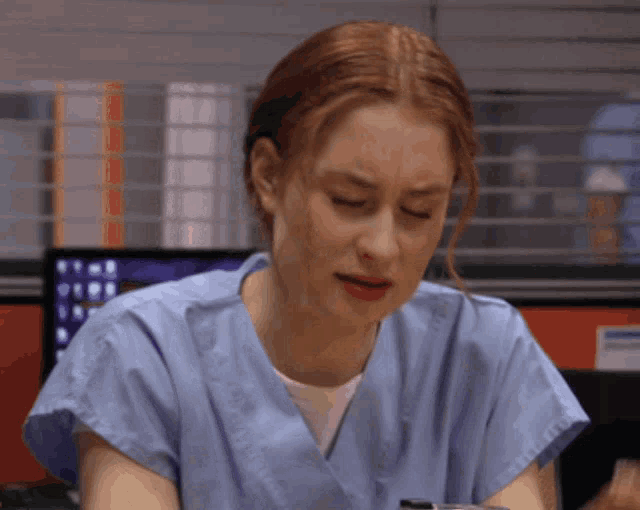 a woman in a blue scrub top looks down