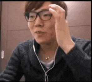 a man wearing glasses and headphones is adjusting his glasses while sitting at a table .