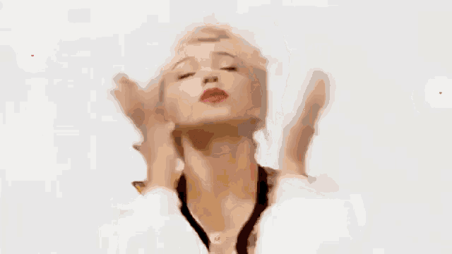 a woman with blonde hair and red lipstick is blowing a kiss with hearts around her .