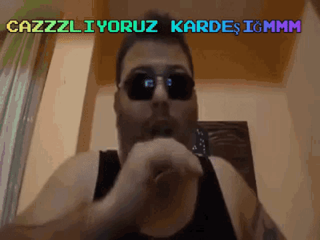 a man wearing sunglasses and a black tank top says cazzliyorum kardes ighmm
