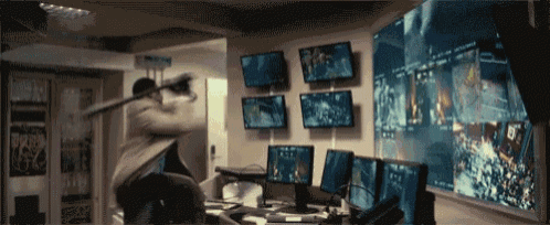a man is standing in front of a wall with monitors and a sign that says b4