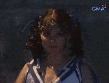 a woman in a cheerleader costume is dancing on a stage in front of a sign that says gma