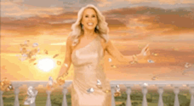 a woman in a gold dress is standing on a balcony with diamonds falling around her .