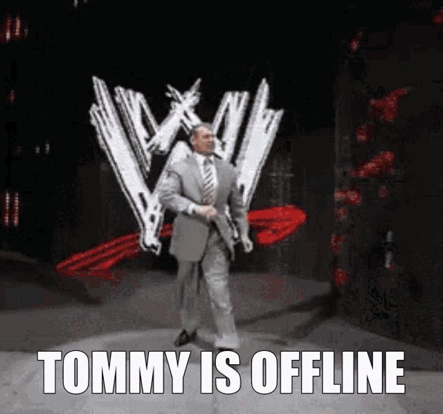 a man in a suit and tie is walking on a stage in front of a tommy is offline logo