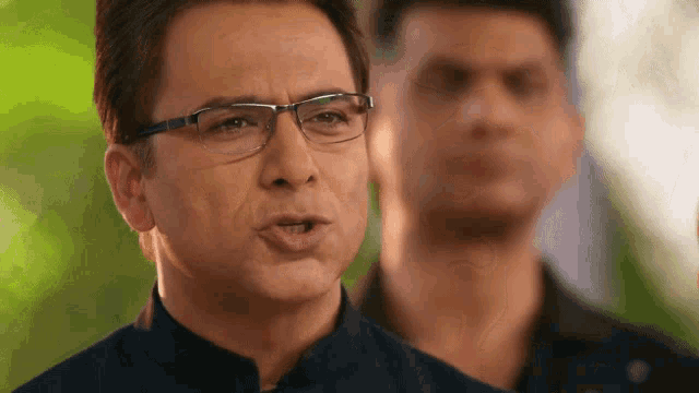 a man wearing glasses and a black shirt looks at the camera