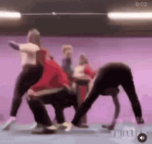 a group of people are dancing in a room with a purple background .