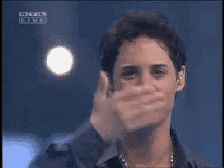 a man is covering his mouth with his hand in front of a sign that says cbs live