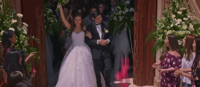 a bride and groom are walking down the aisle of a church surrounded by their wedding guests .