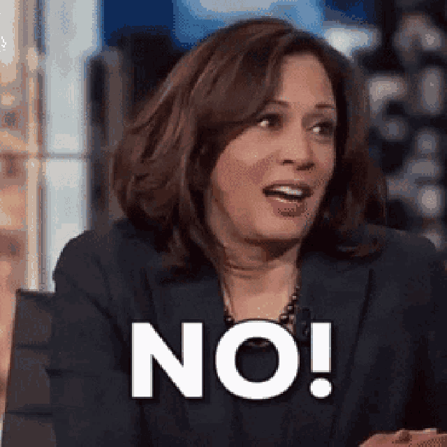 a woman in a suit is sitting in front of a sign that says no !