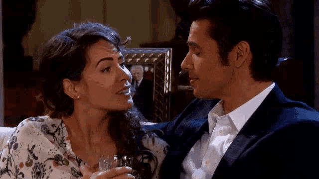 a man and a woman are looking at each other with a picture of a man in the background