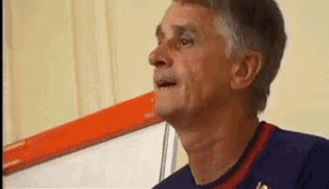 a man in a blue and red shirt is making a funny face with his mouth open .
