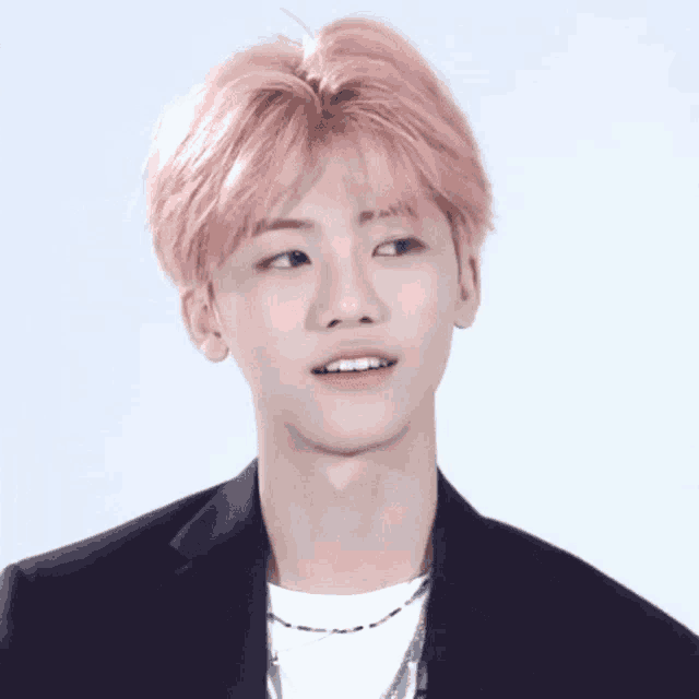 a young man with pink hair is wearing a black suit