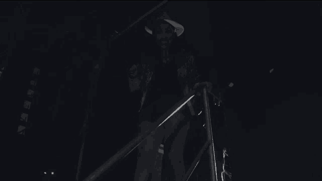 a man in a hat is walking down a set of stairs at night .