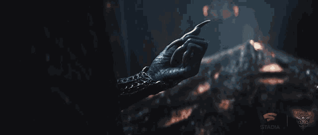a hand is reaching out towards a fire with stadia written on the bottom right