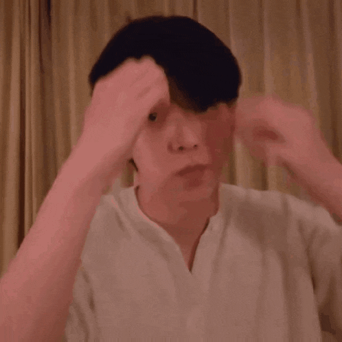 a man with his eyes closed is touching his head with his hands .