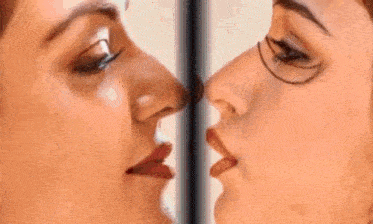 a woman with glasses is kissing another woman on the nose .