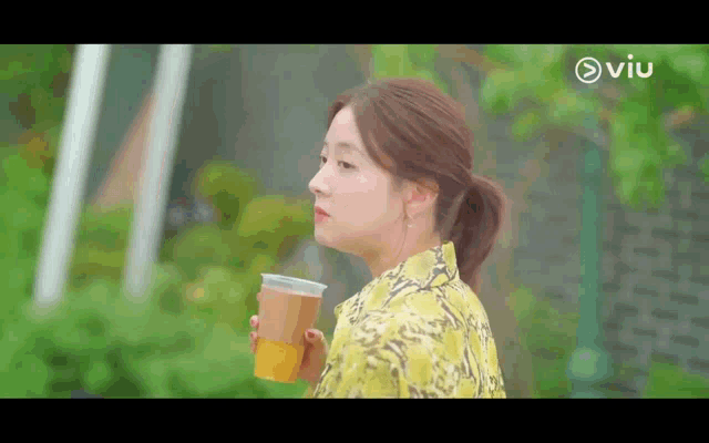 a woman in a yellow dress is holding a cup of tea .
