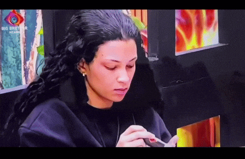 a woman is sitting in front of a big brother screen