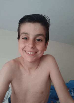 a young boy without a shirt is smiling at the camera