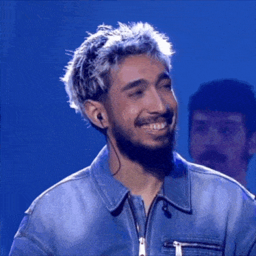 a man with silver hair and a beard is smiling and wearing earbuds