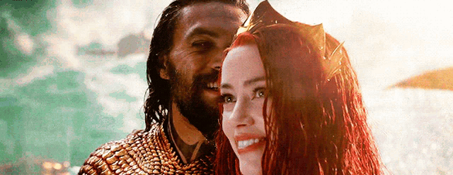 a man and a woman are standing next to each other and smiling . the woman is wearing a crown .