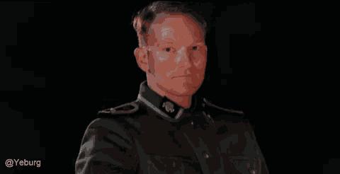 a man in a military uniform is standing in the dark .