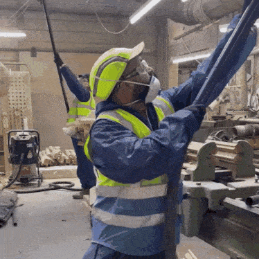 a man wearing a mask and safety vest is working in a workshop