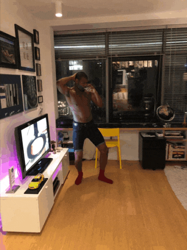 a shirtless man stands in front of a samsung flat screen tv