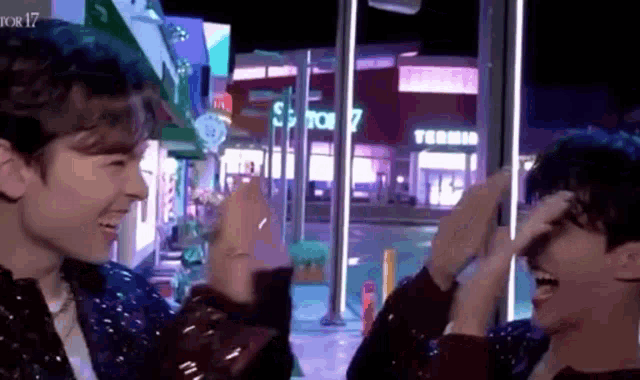 two men are giving each other a high five in front of a city street .