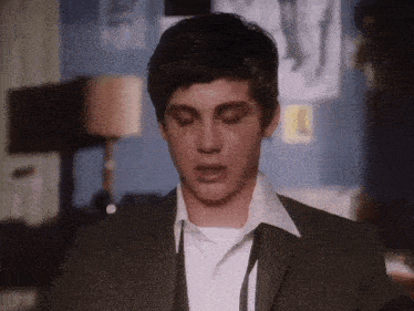 a young man wearing a suit and tie is looking down with his eyes closed