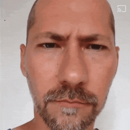 a man with a beard and mustache looks at the camera with a qr code in the corner