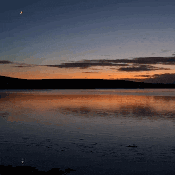 a lake with a crescent moon in the sky