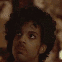 a close up of prince 's face with a beard and curly hair .