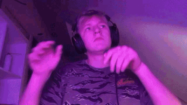 a man wearing headphones and a microphone is standing in front of a purple light .