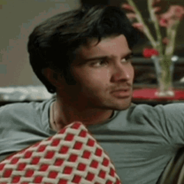 a man sitting on a couch with a checkered pillow in front of him