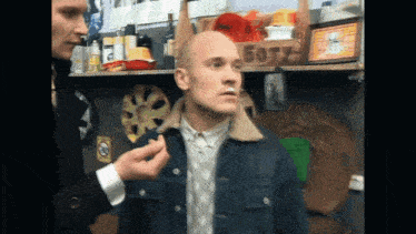 a man in a denim jacket is standing in front of a box that says boty on it