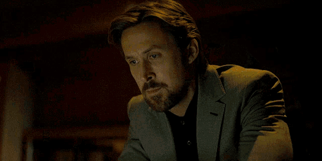 a man in a suit is standing in a room with a bookshelf
