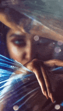 a close up of a woman 's face with a blue feather in her hand .
