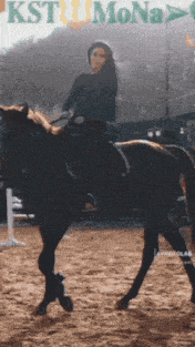 a woman riding a horse in front of a sign that says kst mona
