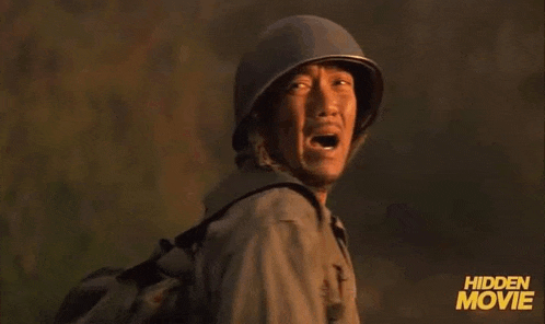 a man wearing a helmet and a backpack is walking through a field with his mouth open .