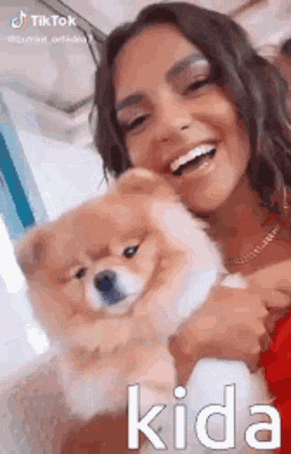 a woman is holding a small dog in her arms .
