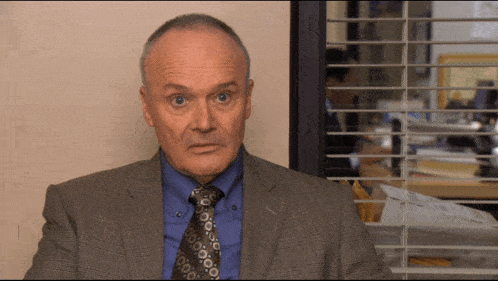 a man in a suit and tie looks at the camera with a serious look on his face